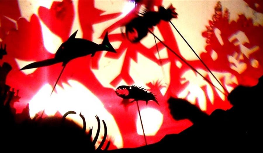 shadow puppets of underwater creatures against a red and white background.