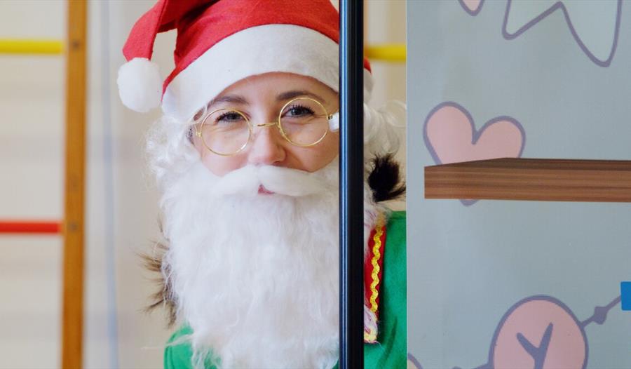 A Christmas elf wears a Santa beard