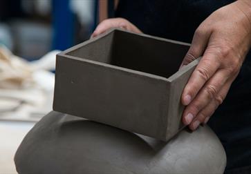 close up of potter's hands with clay box.