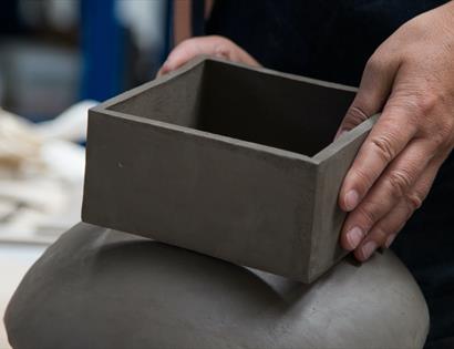 close up of potter's hands with clay box.