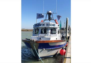 fishing boat in harbour with name dawn tide painted on top