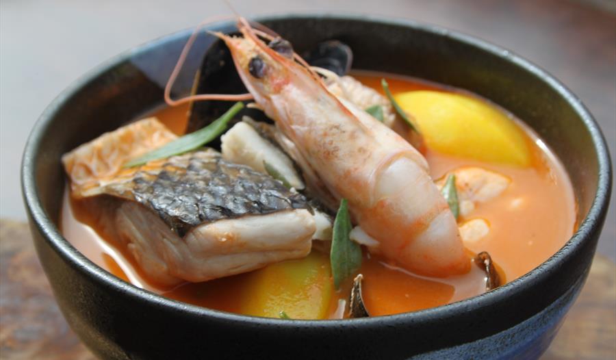 Photograph of seafood including a king prawn in a bowl.