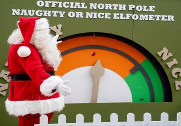 Father Christmas stood by a large gauge marked at each end as naughty and nice.