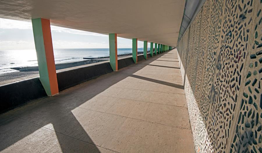 photograph of a roofed concrete promenade looking out to the sea.