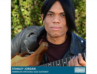 poster for stanley jordan concert, man with dark hair and leather jacket holds guitar