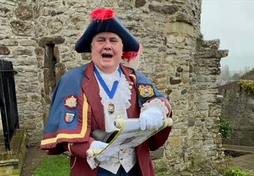 photograph of town crier in traditional costume reading from a scroll