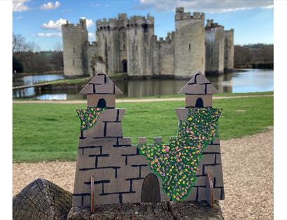 small cutout castle design placed in front of turreted castle and moat