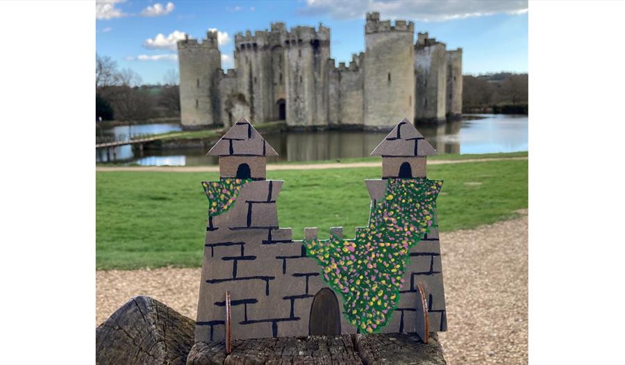 small cutout castle design placed in front of turreted castle and moat