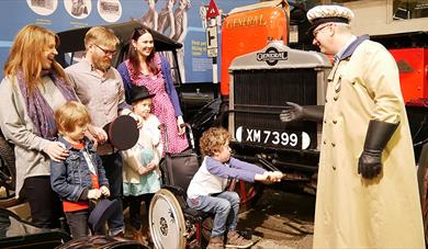 Costumed explainer Jim with a visiting family next to Bessie the Bus