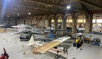 Large, vintage aircrafts on display in a hangar.
