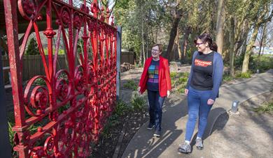 Vibrant red gates at Strawberry Field with two people looking at them.
