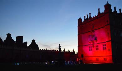 Little Castle at Bolsover Castle lit by red light against an evening sky
