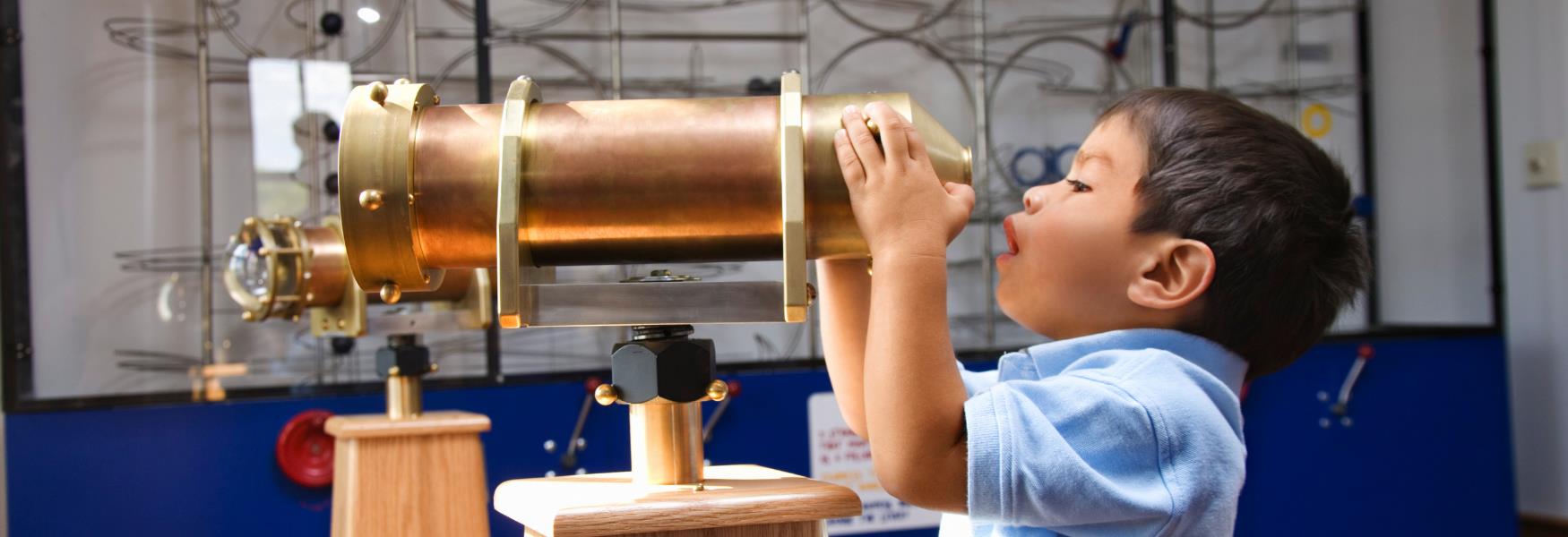 boy peering through telescope