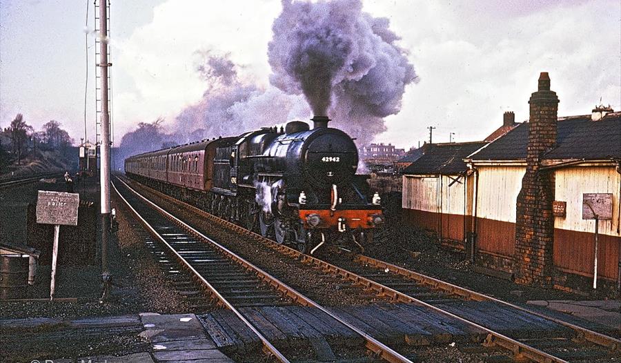 A steam train comes through a station