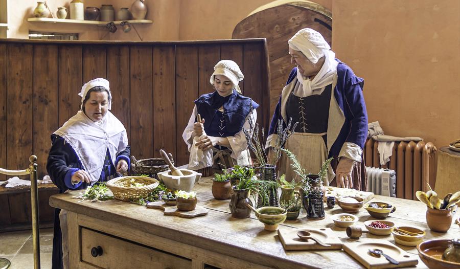 Volunteers in Tudor costume cooking in the Buckland Abbey Kitchen