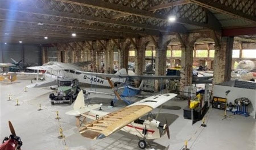 Large, vintage aircrafts on display in a hangar.