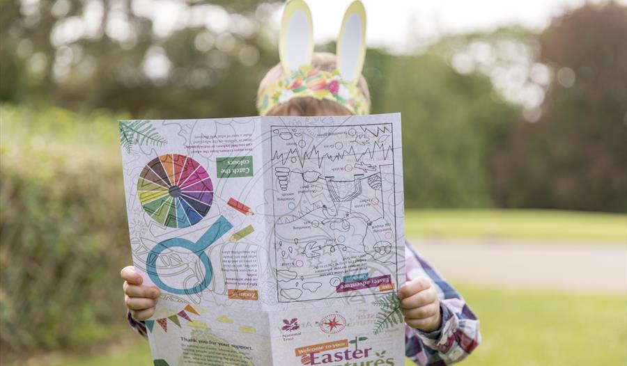 Child with bunny ears hidden behind a trail sheet.