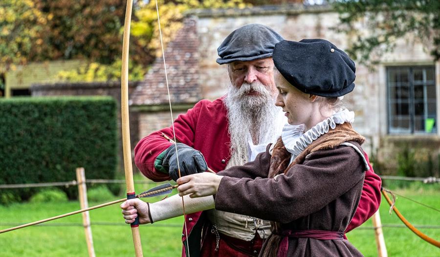 Anne Martyn recieves an archery lesson outside