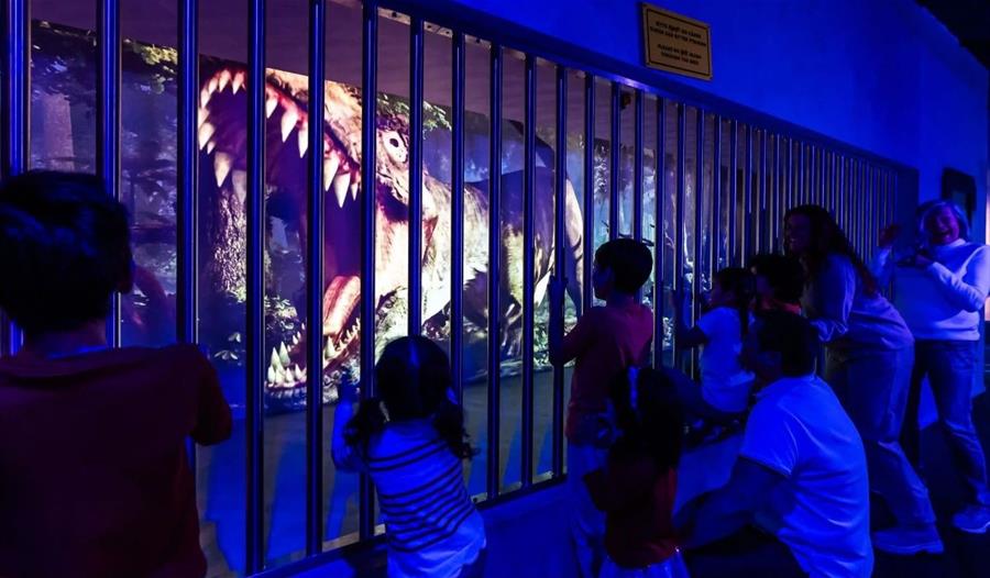 Families looking at a projection of a dinosaur