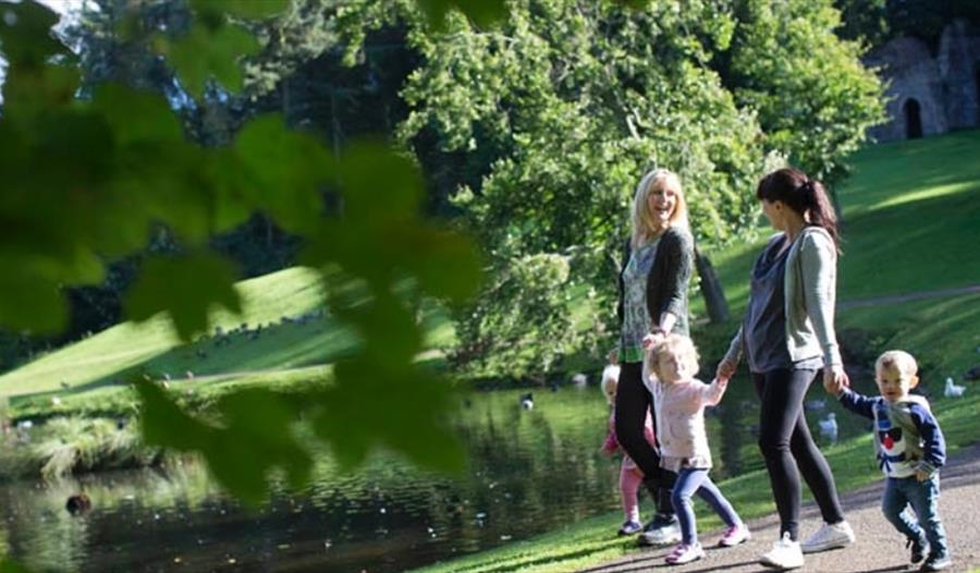 Two women and three children walking around the lake at Hardwick Park