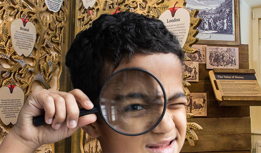 A young boy holding a magnifying glass to his face