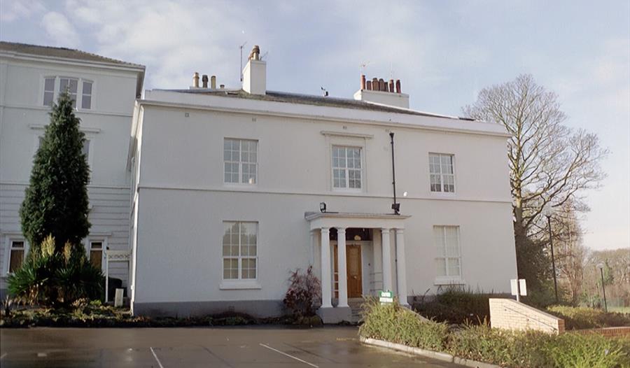 A historic white building set within grounds.