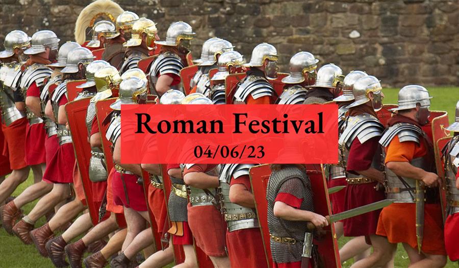 A group of men dressed in Roman centurion outfits marching along a field with the text 'Roman Festival 4/6/23' overlaid.