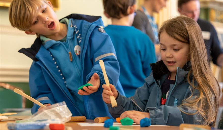 Two children trying a craft activity at The Roman Baths