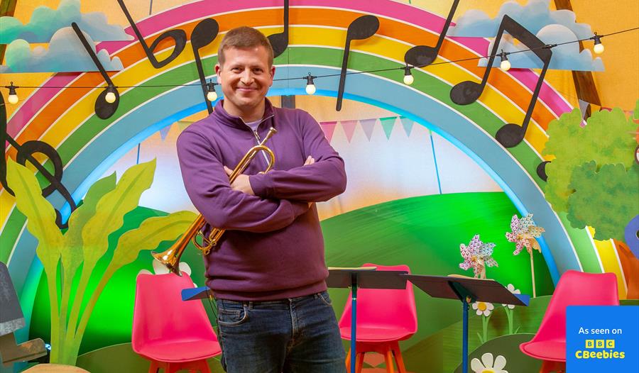 Present standing in front of a rainbow and trumpet