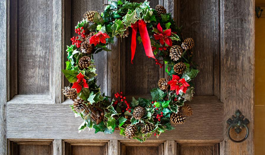Red and green Christmas wreath on a wooden door.
