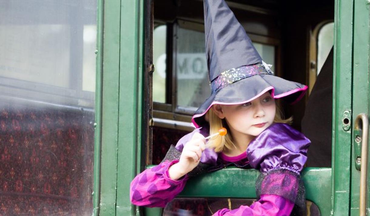 Girl dressed up as a witch looking out of the carriage window at the Wizard Week event, Isle of Wight Steam Railway, what's on