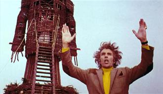 Man in front of a large figure made of sticks