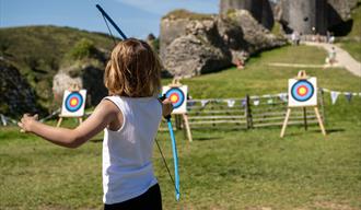 A child playing archery in the castle ruins.