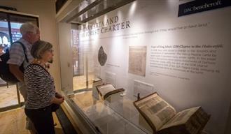 Two visitors to the Cathedral Museum looking at the Magna Carta display from 2017