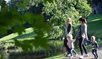 Two women and three children walking around the lake at Hardwick Park