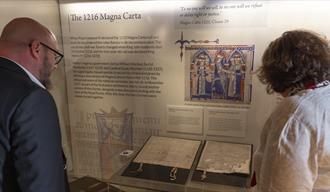 Two people looking at the 1216 Magna Carta at Durham Cathedral Museum