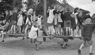 Black and white photo of children plaing in a playground.