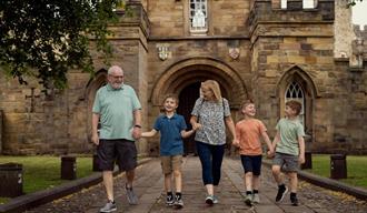 A family walking in front of the gateway of Durham Castle