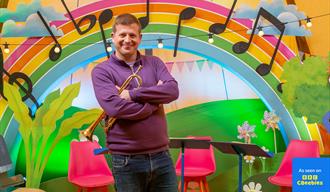 Present standing in front of a rainbow and trumpet