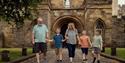 A family walking in front of the gateway of Durham Castle