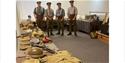 Men in First World War British Army uniforms stand behind tables with Great War military equipment, including webbing, helmets and packs