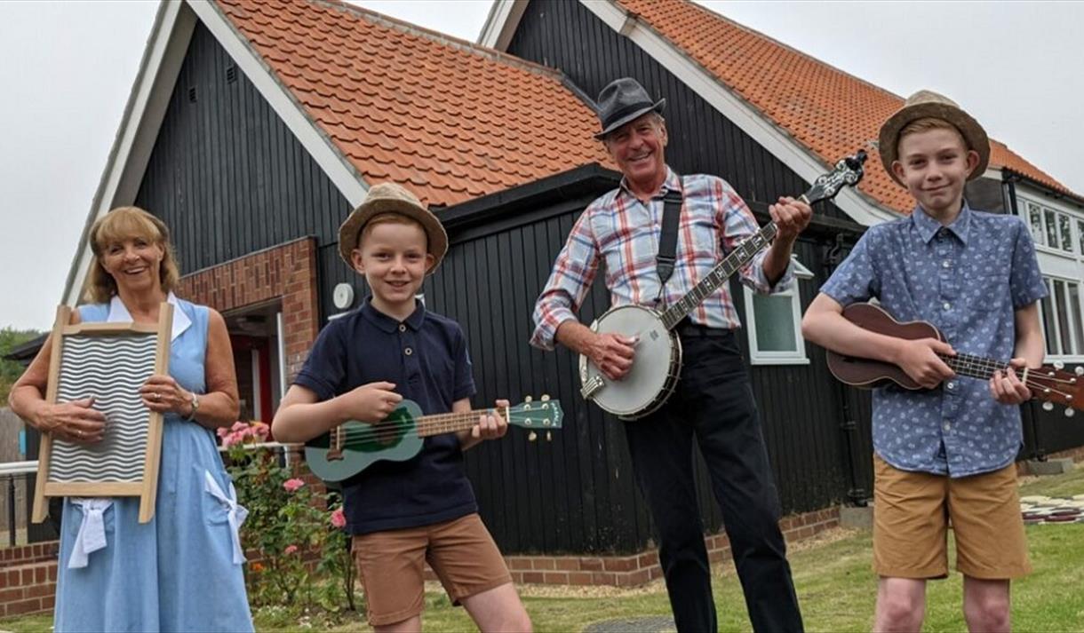 A family of musicians standing outside of Beamish Welfare Hall.