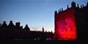 Little Castle at Bolsover Castle lit by red light against an evening sky