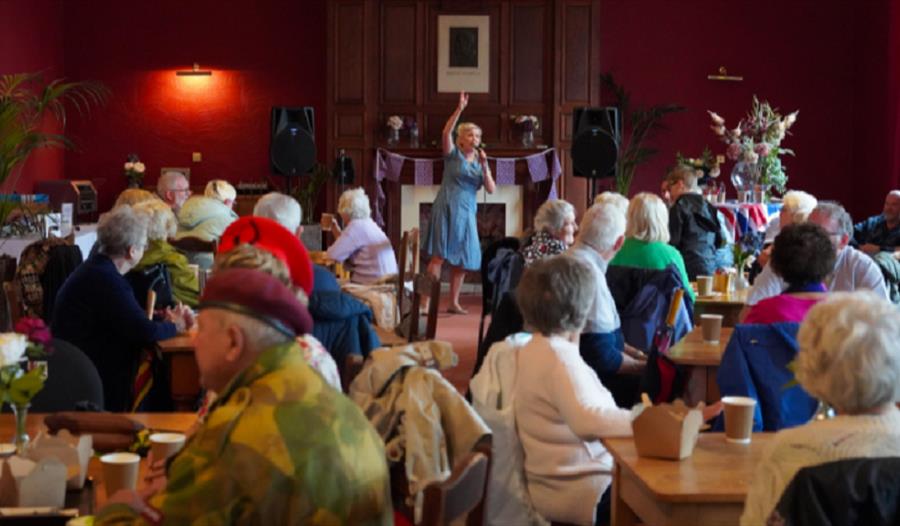 A crowd sitting at tables enjoying a 1940s musical entertainer.