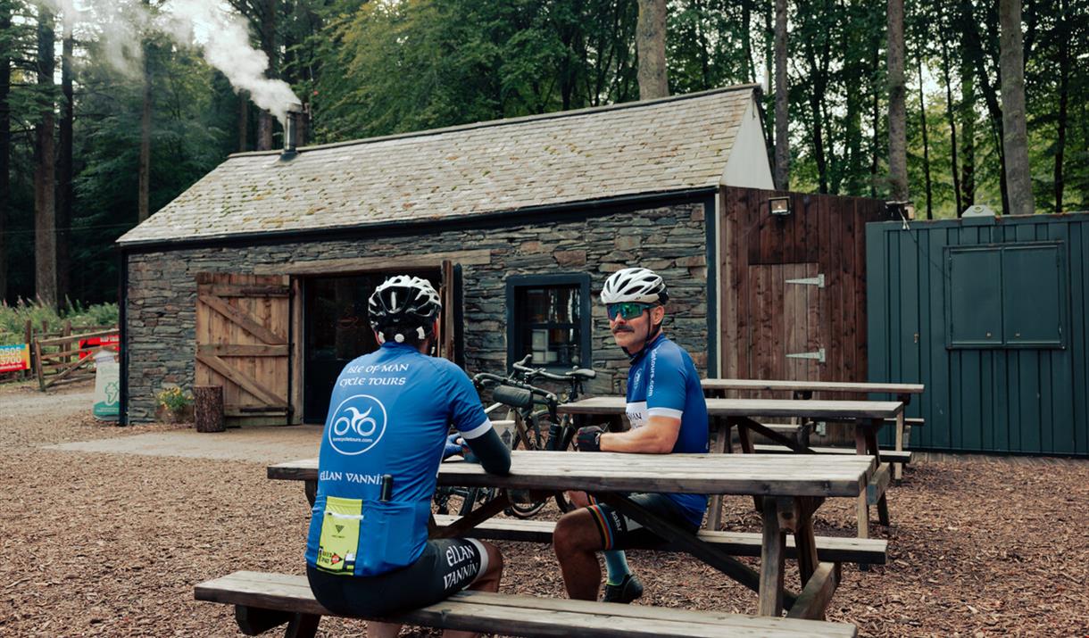 Cyclists on picnic bench seating outside The Coffee Cottage