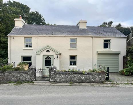 Nestled in a tranquil rural setting, Bridge House Dalby is a picturesque two-story home with a classic white exterior and a grey roof.