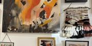 Inside Pink Seaweed gallery, filled with bold, earthy artwork in rich oranges and browns — a vibrant, ever-changing collection created by local artist