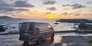 Campervan parked at Niarbyl Bay with sunset in the background