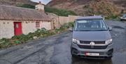 Campervan parked at Niarbyl Bay with cottage in background