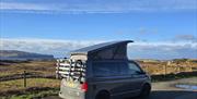 Campervan with the pop-top raised on the Isle of Skye with coast in the distance